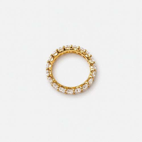 Gold ring with embedded diamonds on a light gray background
