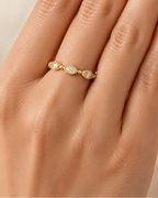 Gold ring with small stones on a hand against a beige background