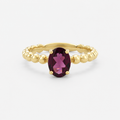 Gold ring with a purple gemstone on a white background