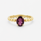 Gold ring with a purple gemstone on a white background