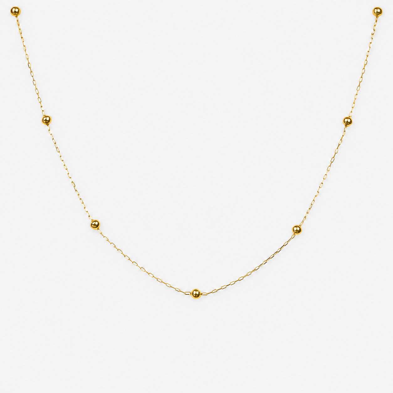 Gold necklace with small beads on a white background