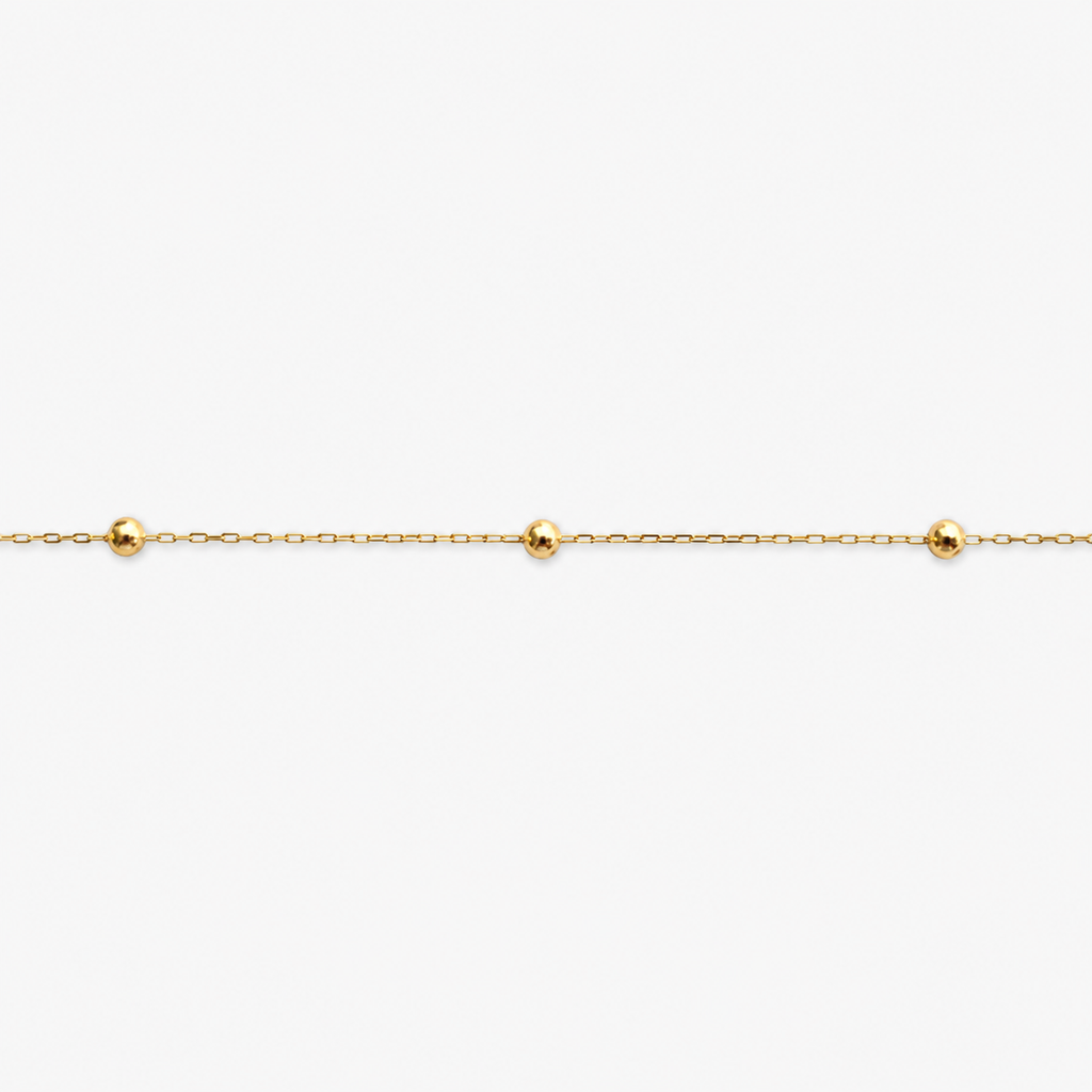 Gold bracelet with small beads on a white background