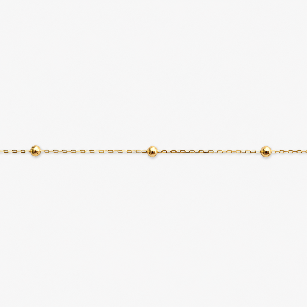 Gold bracelet with small beads on a white background