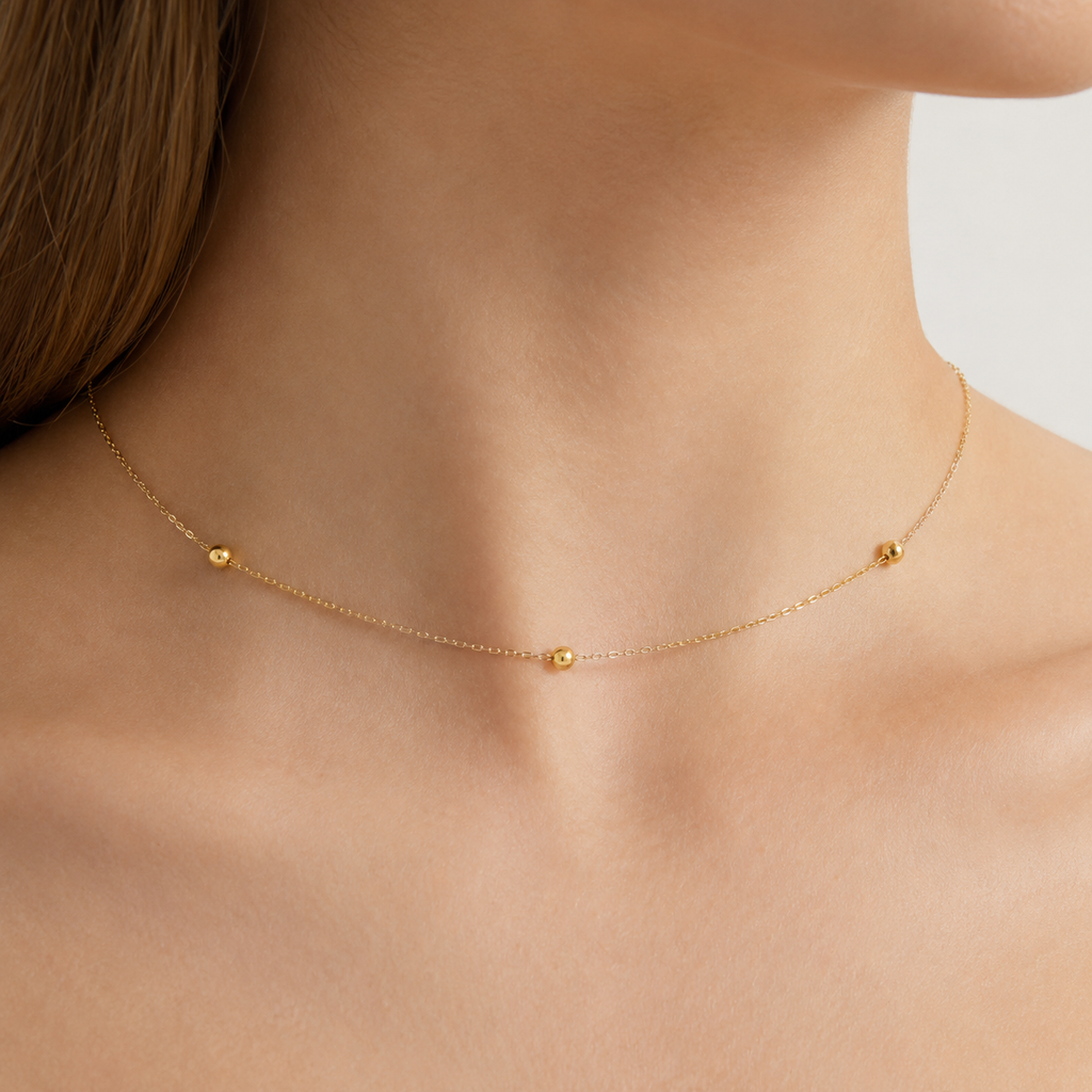 Gold necklace on a person's neck with a plain background
