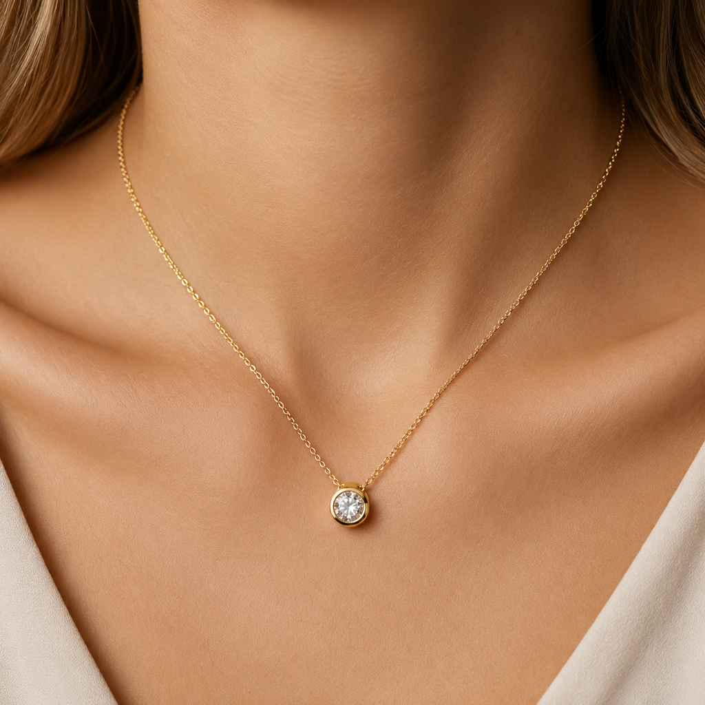 Gold necklace with a small round pendant on a person's neck