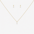Gold necklace and earrings with pearl drops on a white background