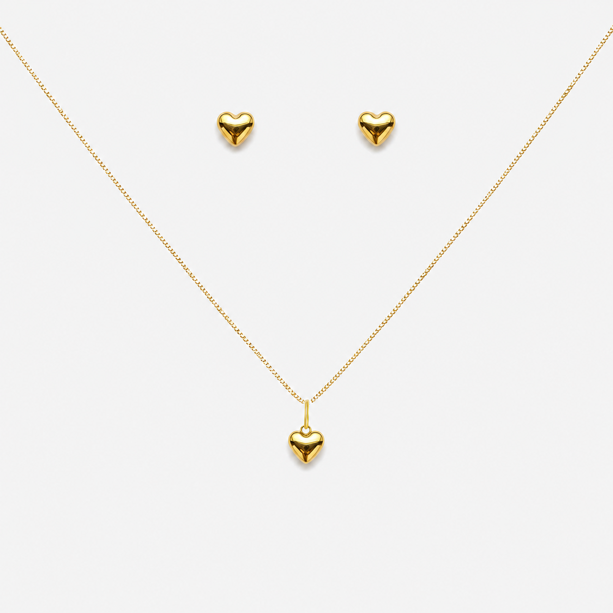 Gold heart necklace and earrings on a white background