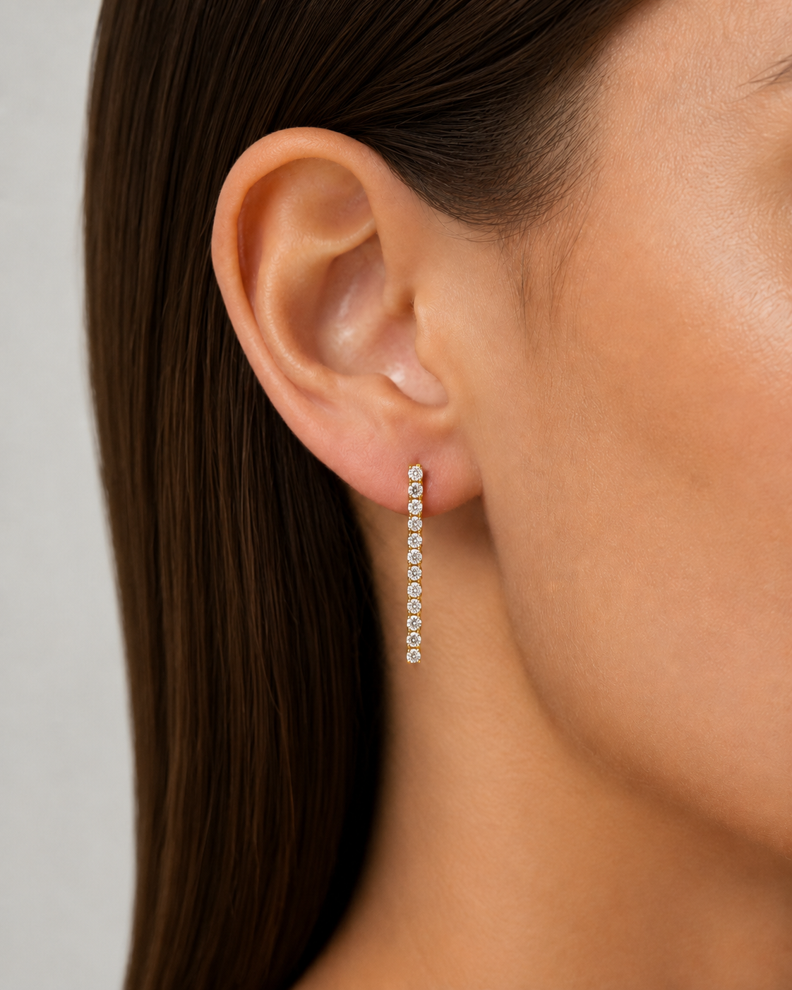 Close-up of an ear wearing a pearl earring with a neutral background