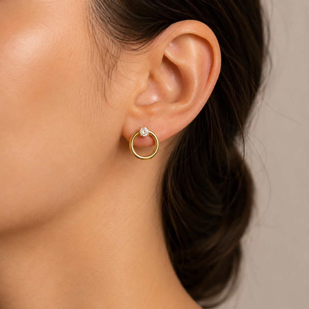 Close-up of an ear wearing a gold hoop earring with a diamond.