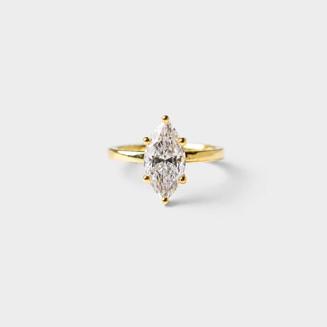Gold ring with a pear-shaped diamond on a light gray background