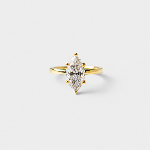 Gold ring with a pear-shaped diamond on a light gray background