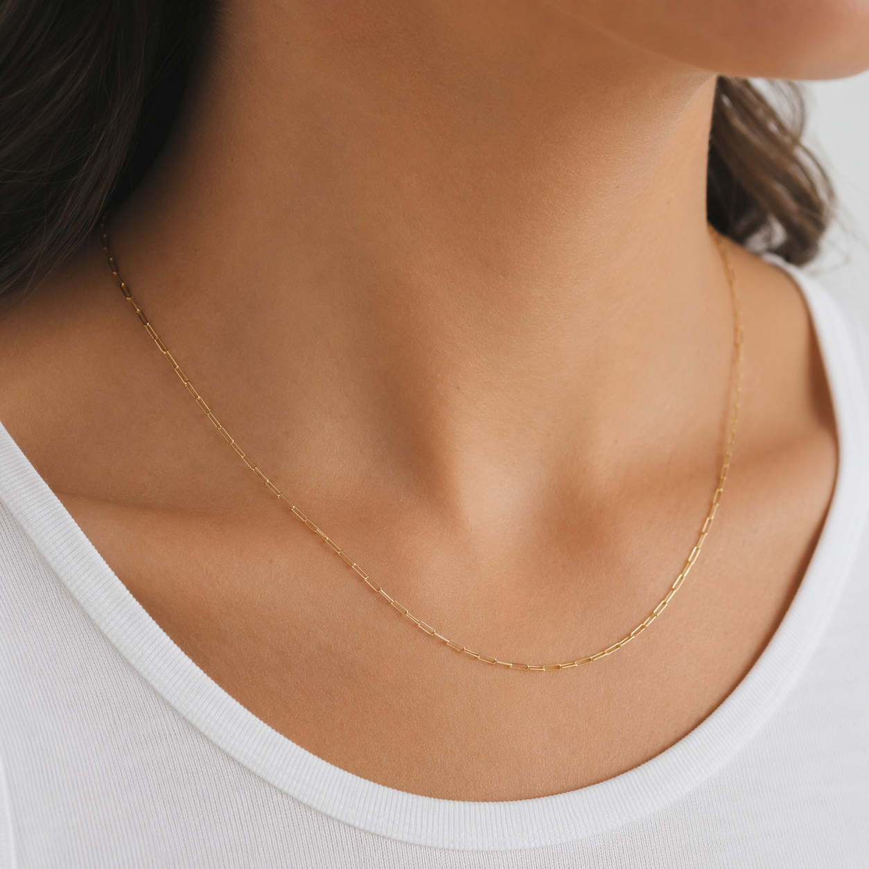 Gold necklace on a person wearing a white top