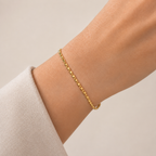 Gold bracelet on a person's wrist against a neutral background