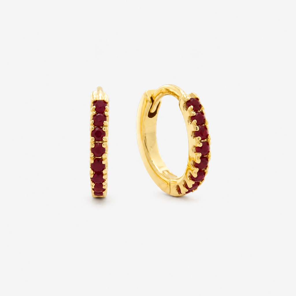 Gold hoop earrings with red gemstones on a white background