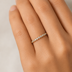 gold ring with small diamonds on a hand against a neutral background