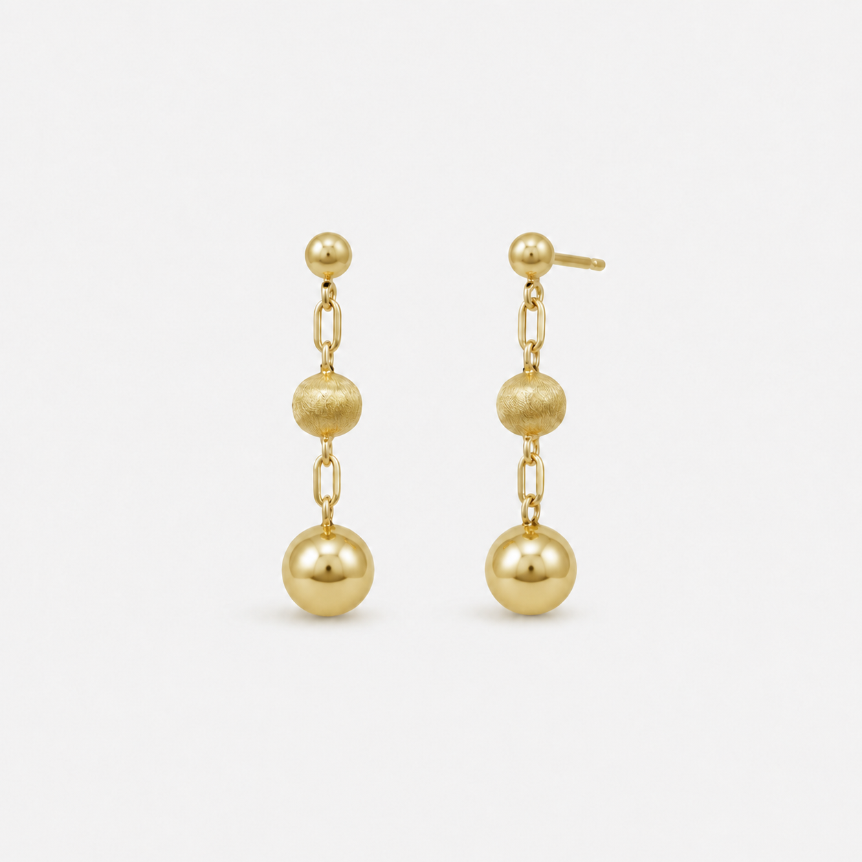 Pair of gold earrings with spherical beads on a white background